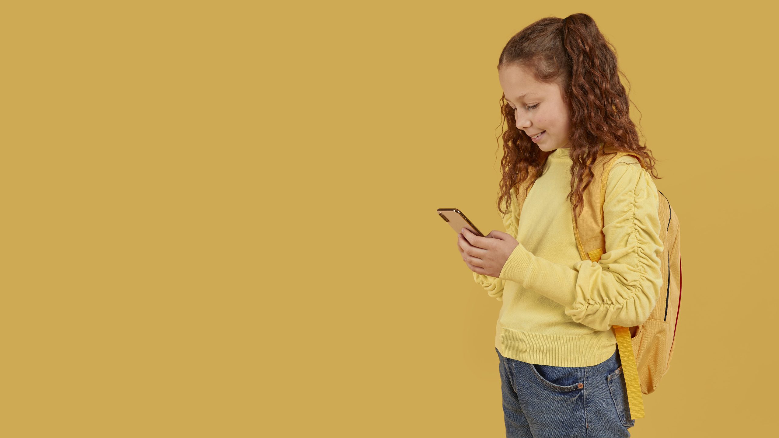 school-girl-with-yellow-shirt-looking-phone-copy-space